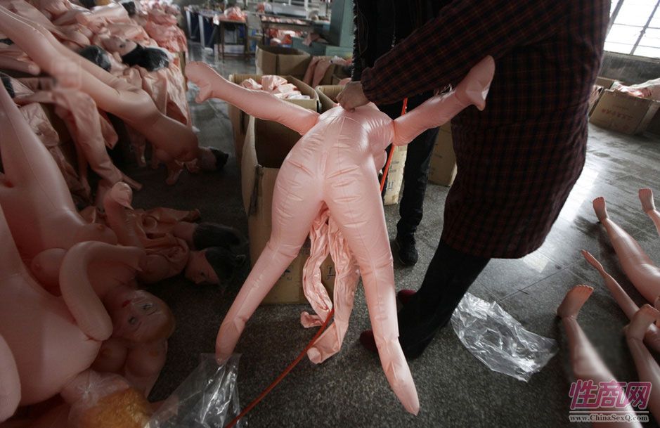 图为2012年2月13日,浙江宁波一家充气娃娃生产厂内,工人在搬运充气娃娃。
