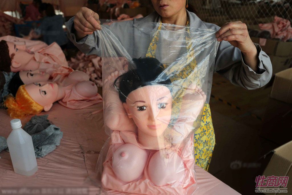 一名女工将完成充气检验后的娃娃被包装好。